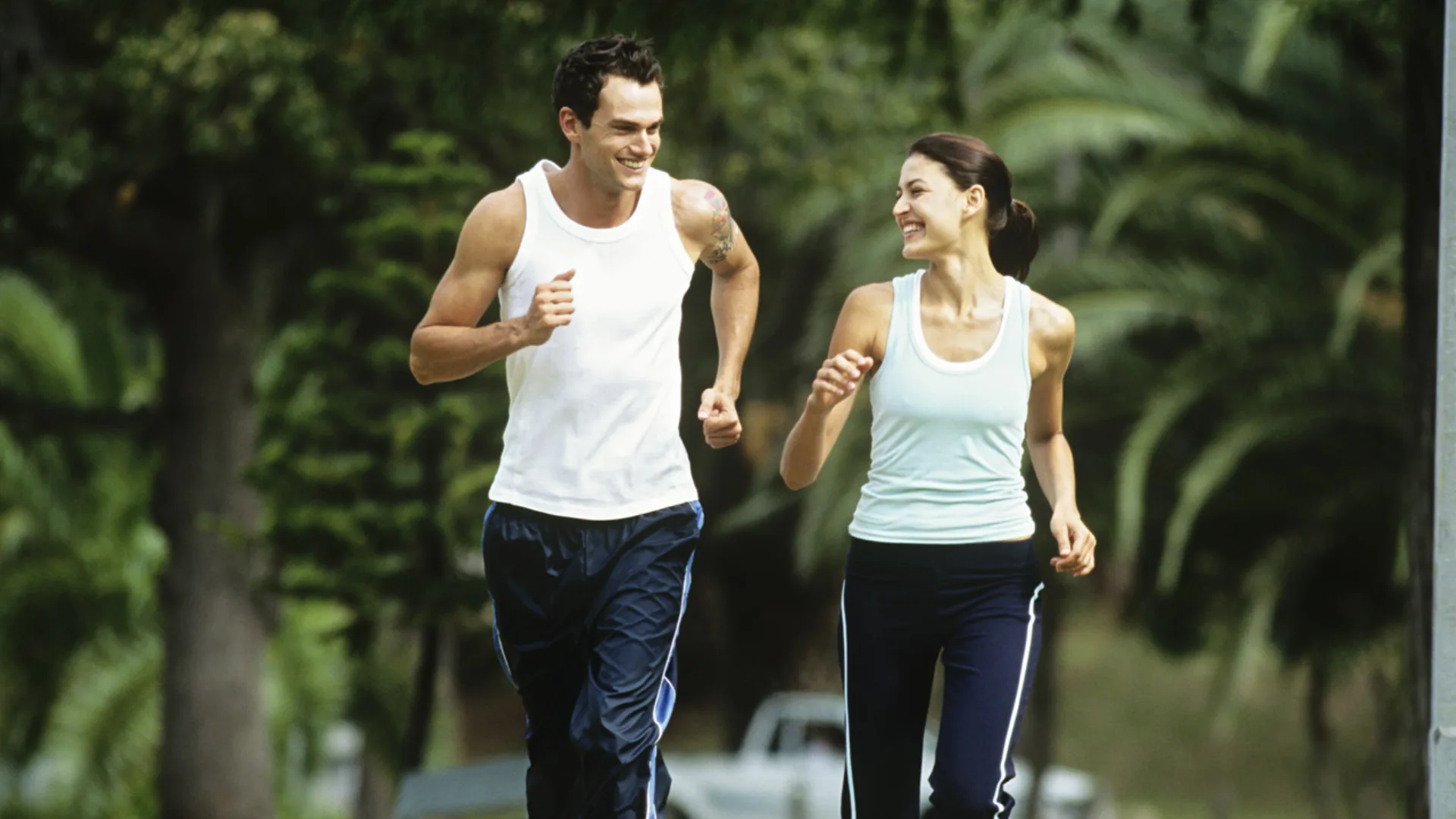 A couple enjoys a refreshing morning run through the lush greenery of the park, embracing fitness and the joy of outdoor activity.