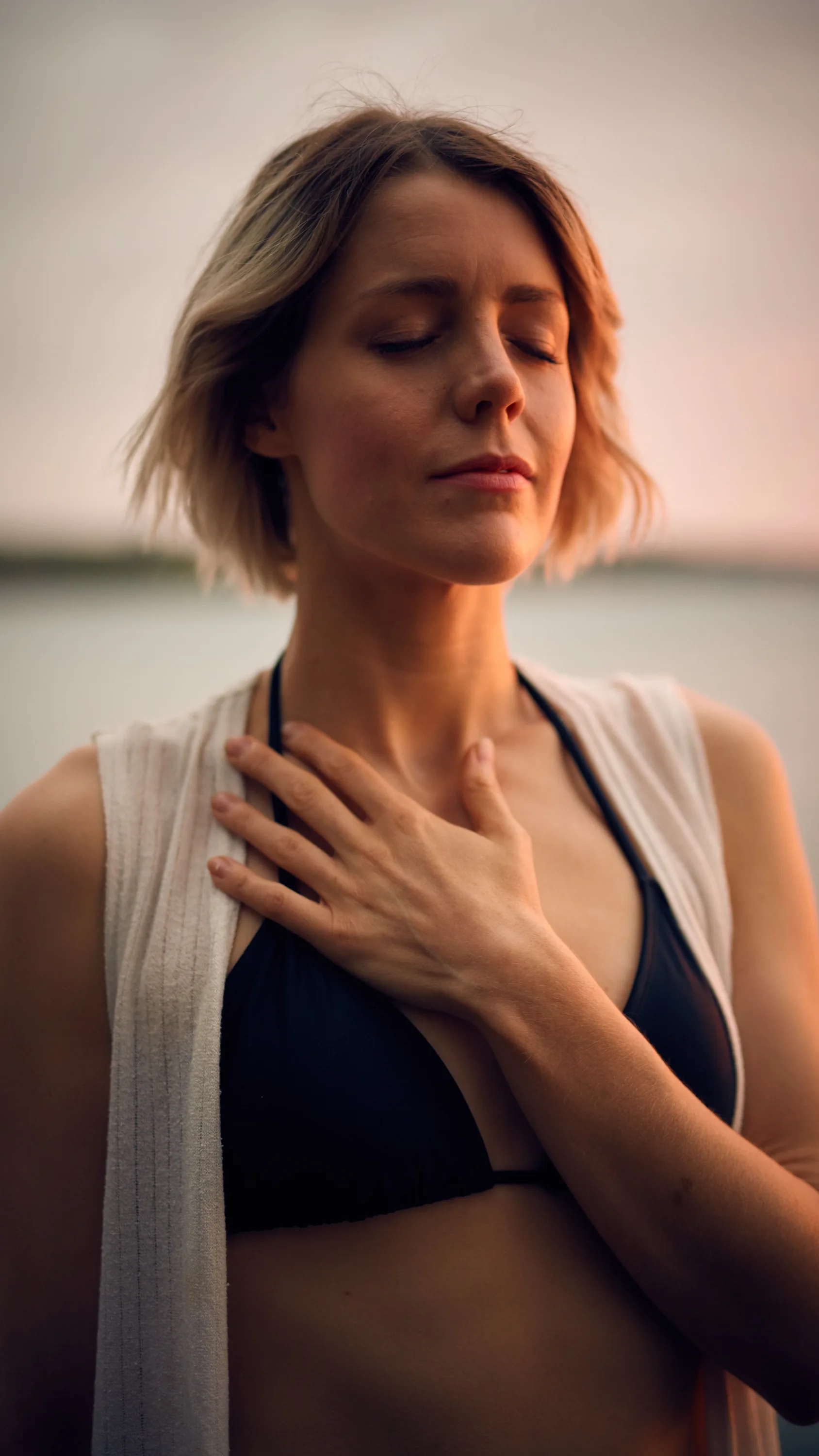 A person practices belly breathing, focusing with eyes closed and a hand on the chest, surrounded by a serene atmosphere.